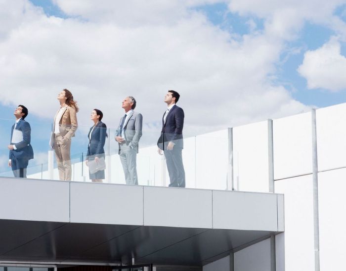 Business people on rooftop balcony looking up at sky
